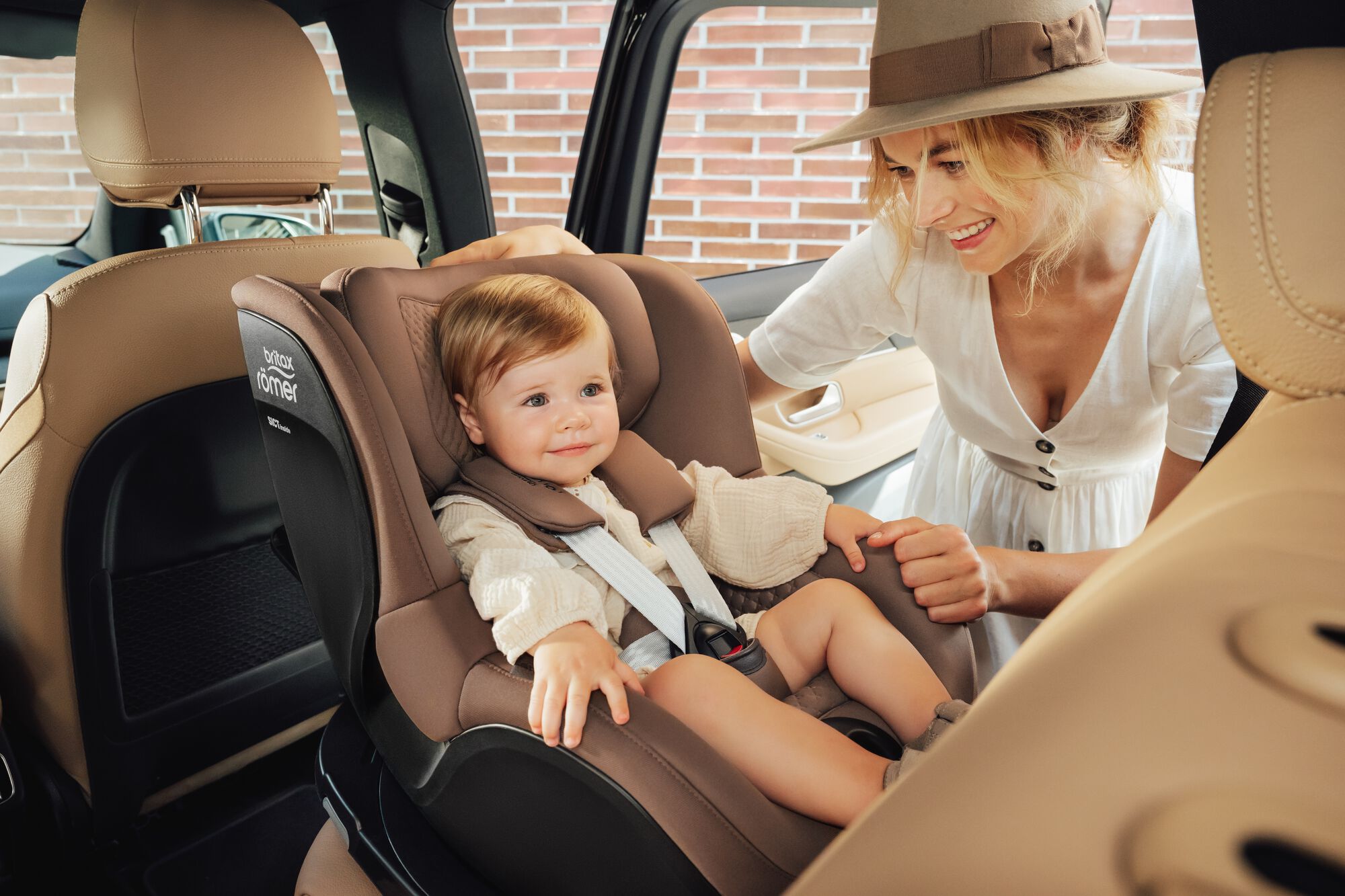 Toddler secured in a DUALFIX 5Z toddler car seat, with his mother standing by his side.
